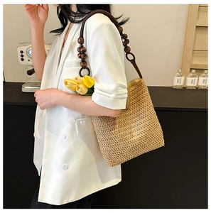 Detail of handmade rainbow straw bucket bag featuring dark brown wooden bead shoulder strap