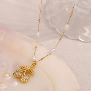 Detail of 18K gold-plated necklace featuring pearl beads and a crystal cherry pendant