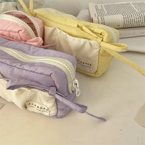 Detail of multi-layer fabric pencil cases in pastel purple, yellow, and pink colors