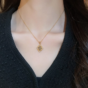 Close-up of a gold-plated vintage clover pendant necklace on a model wearing a black top