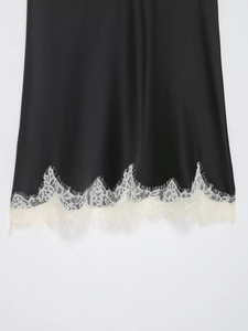 Détail de l'ourlet en satin noir avec bordure en dentelle blanche sur caraco