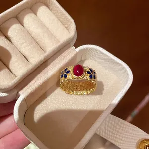 Detail view of retro bamboo style ring with red oval gemstone and blue enamel flowers