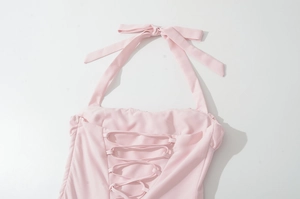 Close-up of pink halter neck dress featuring intricate lace-up strap details on smooth fabric
