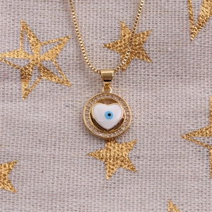 Collier doré avec pendentif cœur œil protecteur en zircons sur tissu étoilé beige
