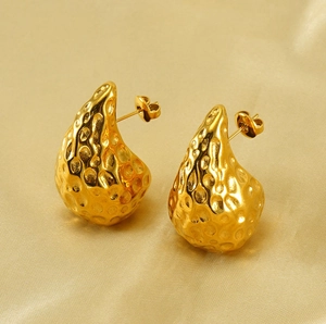 Macro shot of 18K gold hammered teardrop earrings on elegant silk background