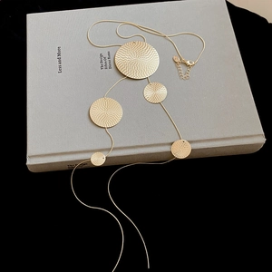 Detail of gold geometric round textured pendants on minimalist tassel chain necklace