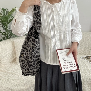 Detail shot of leopard print tote bag styled with white blouse and grey pleated skirt