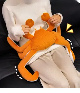 Close-up of a large orange plush king crab toy held by a person on a sofa