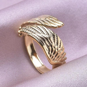Detailed macro view of the gold-plated angel wing ring on premium purple silk fabric