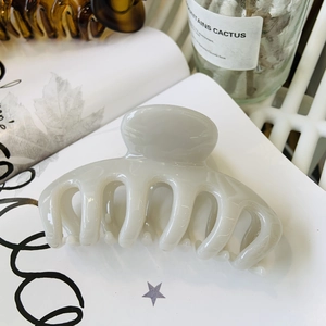Close-up of cream-colored floral claw clip on book with soft natural lighting decor