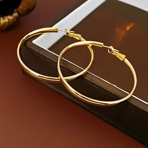 Boucles d'oreilles créoles dorées classiques sur une boîte à bijoux en bois brun