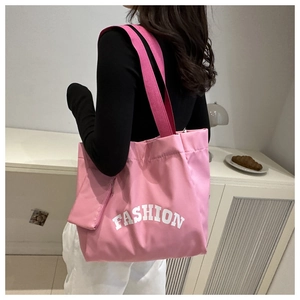 Pink oxford fabric tote bag with large FASHION print shown on model in a cozy room