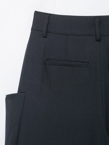 Detail of the high-waisted back design with single welt pocket on dark trousers