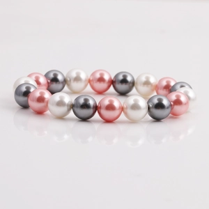 Rosa, graue und weiße Muschelperlen für DIY-Armbänder auf reflektierendem weißem Grund