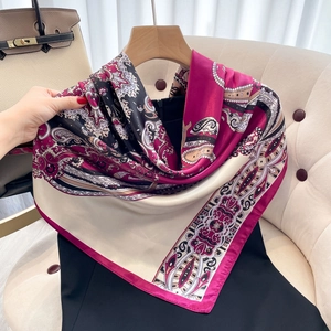 Elegant pink and beige paisley silk scarf for women styled on a black dress and chair