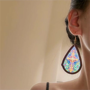 Detail of vintage teardrop earring with stained glass cross pattern on model