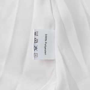 Detail shot of the 100% polyester fabric care label on a white printed mini dress