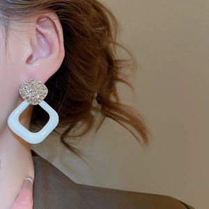 Nahaufnahme eines Models mit silbernen geometrischen Ohrringen mit weißem Emaille