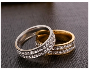 Close-up of gold and silver double row square zircon rings on black leather background