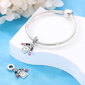Detail of silver lipstick and perfume bottle charm with red enamel and sweet engraving