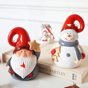 Luminous Santa Claus and snowman ceramic ornaments on a vintage book with festive lights