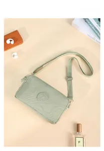 Vista piatta della borsa a tracolla in nylon verde chiaro con tracolla e accessori