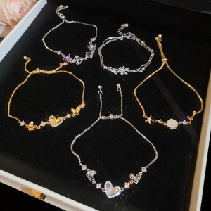 Detailed close-up of a zircon heart and flower charm bracelet set on a black velvet tray