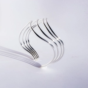 Minimalist silver wide wave bangle featuring a multilayered open curved design in high polish