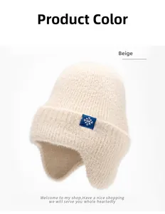 Gros plan du bonnet en tricot beige montrant la texture et l'écusson flocon