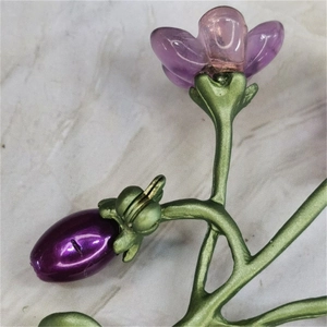 Artistic violet flower brooch with green metal leaves and freshwater pearls on marble
