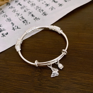 Detail of silver bamboo style bracelet featuring lotus bud and butterfly charms