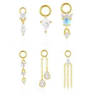 Macro detail of gold earring pendants featuring clear cubic zirconia and light blue stones