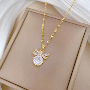 Macro shot of gold butterfly necklace pendant with white zircon inlays on white silk