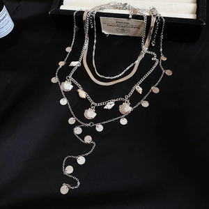 Detail view of layered silver necklace with shell charm and round sequin pendants