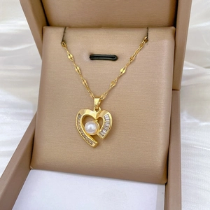 Detailed close-up of heart pearl pendant with zircons in a velvet jewelry box