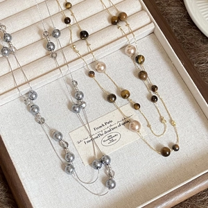 Tiger eye and pearl beaded necklaces in silver and amber gold on a luxury wooden tray