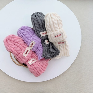Detail der Strickstruktur von warmen Kinder-Mützen in verschiedenen Farben mit Aufnäher