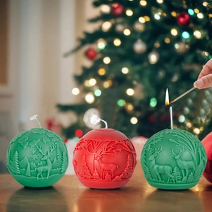 Drie stuks kerstgeurkaarsen met reliëfpatronen van rendieren en bos in groen en rood