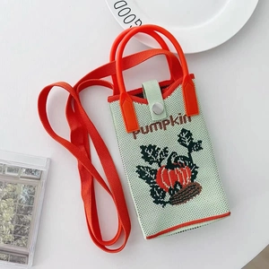 Detail of knitted mint green pumpkin phone bag with bright orange handle and crossbody strap