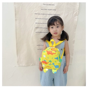 Toddler backpack featuring yellow dinosaur patterns shown on a model for scale and fit