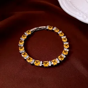 Elegant gold tennis bracelet with square yellow zircons on premium brown silk background