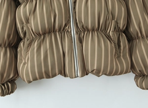 Macro detail of brown vertical striped puffer jacket with metal zipper and hem stitching