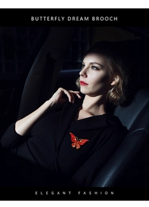 Macro view of crystal butterfly brooch with red wings on elegant model profile