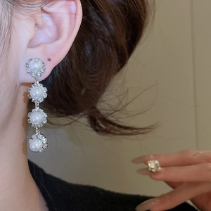 Detail of elegant silver drop earrings with stacked pearls and sparkling crystals