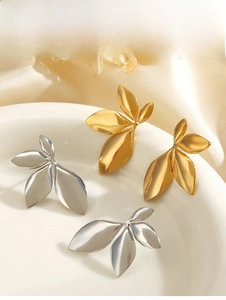 Detail view of gold and silver leaf earrings on a ceramic plate with satin background