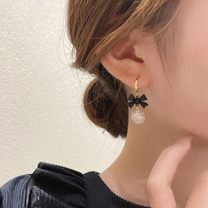 Elegant gold C-shape bow earrings with crystal ball worn by a model in soft light