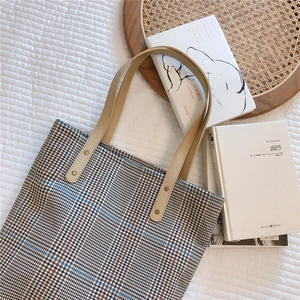 Detail of vintage plaid canvas tote bag with leather handles and metallic rivet accents