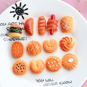Flat lay of resin food charms like burgers and croissants in a white decorative plate
