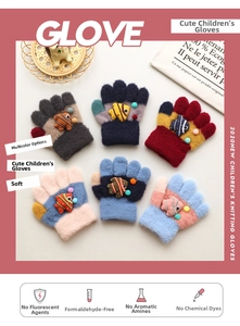 Flat lay of colorful knitted children gloves with 3D fish decor and soft pompoms