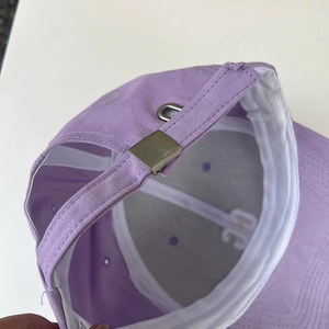 Detail of purple cotton baseball cap featuring silver metal adjustable buckle and internal embroidery